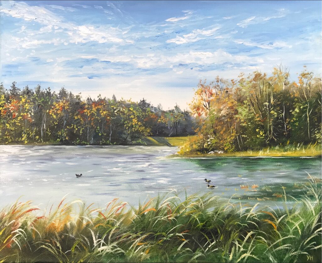 Close view of autumn woodland and waterbirds beside a blue green lake