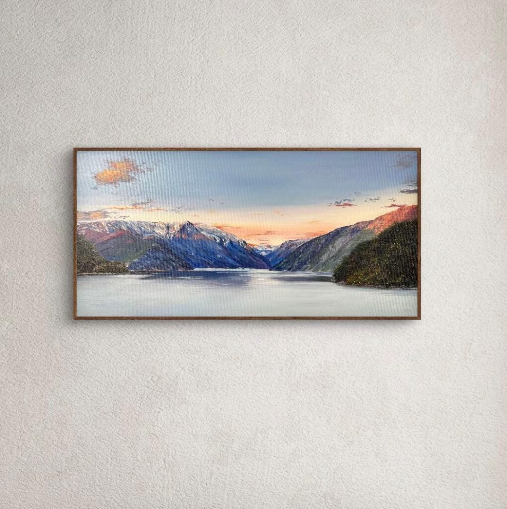 Mountain lake oil painting in a brown frame above a wooden sideboard
