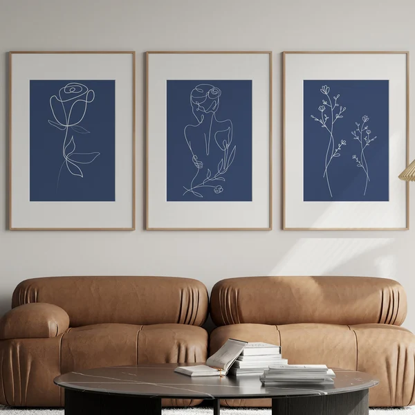 Navy blue line art triptych above a brown sofa