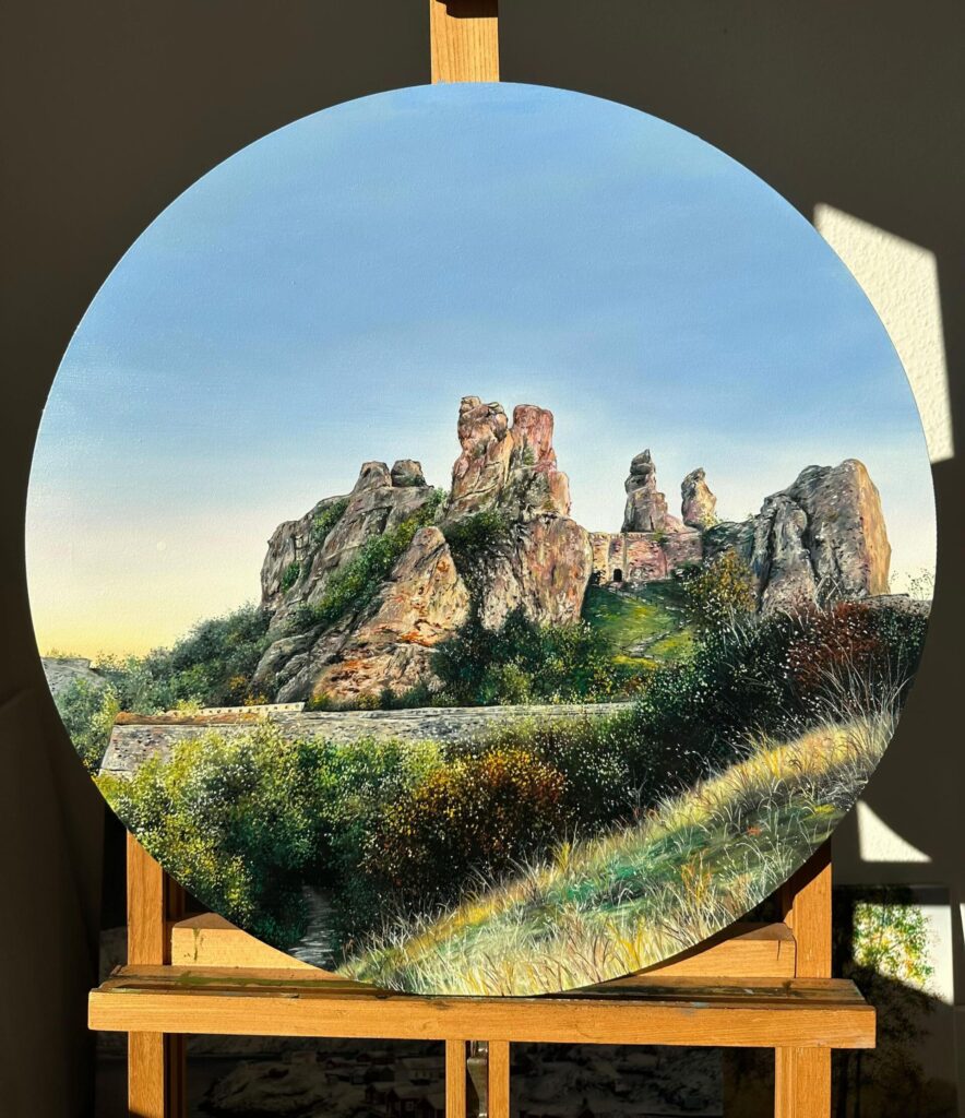 Round landscape oil painting of a rocky fortress on an easel