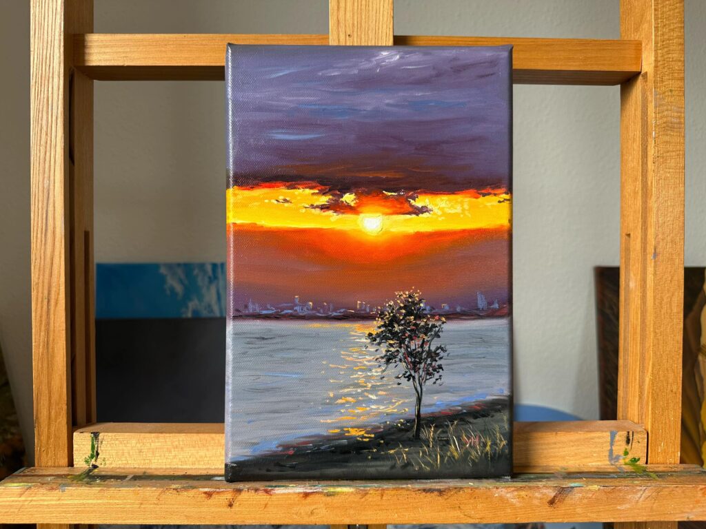 Sunset landscape oil painting displayed on wooden easel