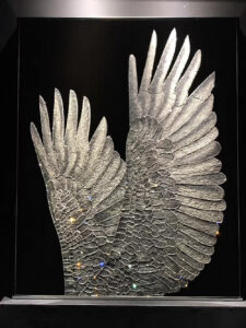 Swarovski crystal wall art with layered silver wings on a dark background