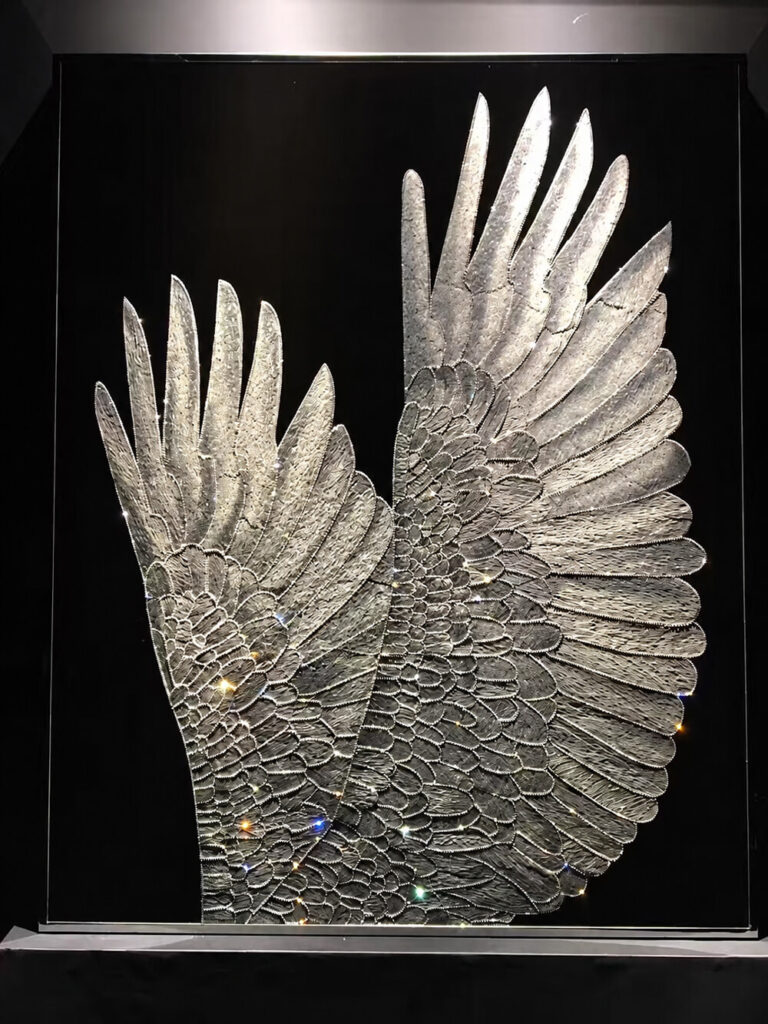 Swarovski crystal wall art with layered silver wings on a dark background