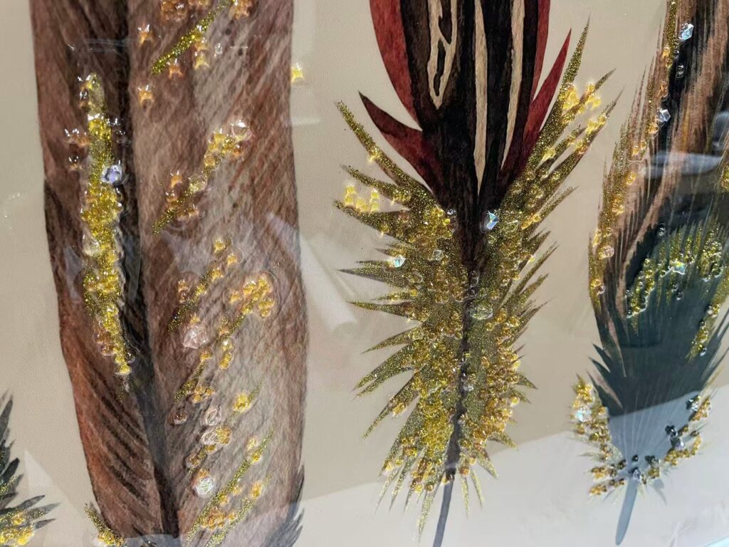 Close-up of crystal and gold powder in feather wall art.