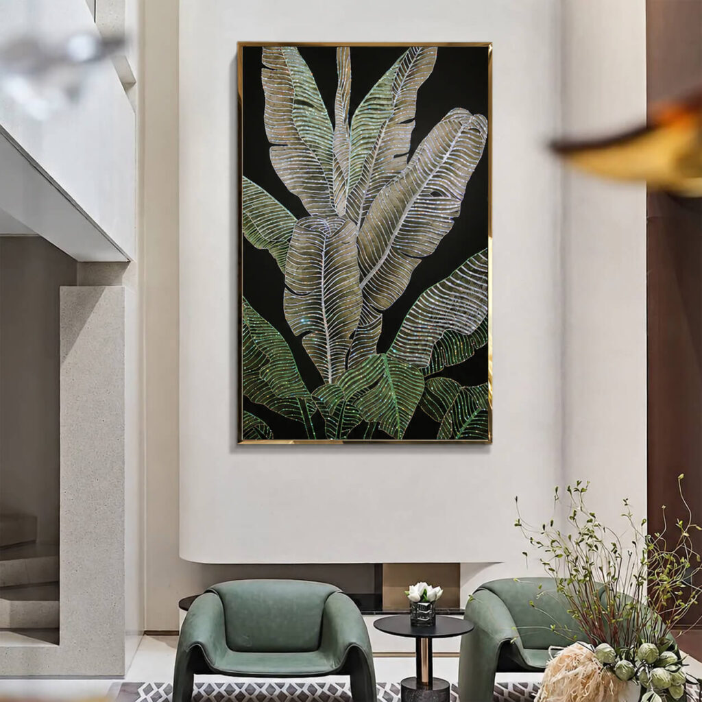 Gold framed crystal leaf artwork in a bright lounge with green chairs