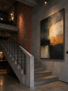 Industrial staircase wall with exposed brick and oversized abstract canvas art