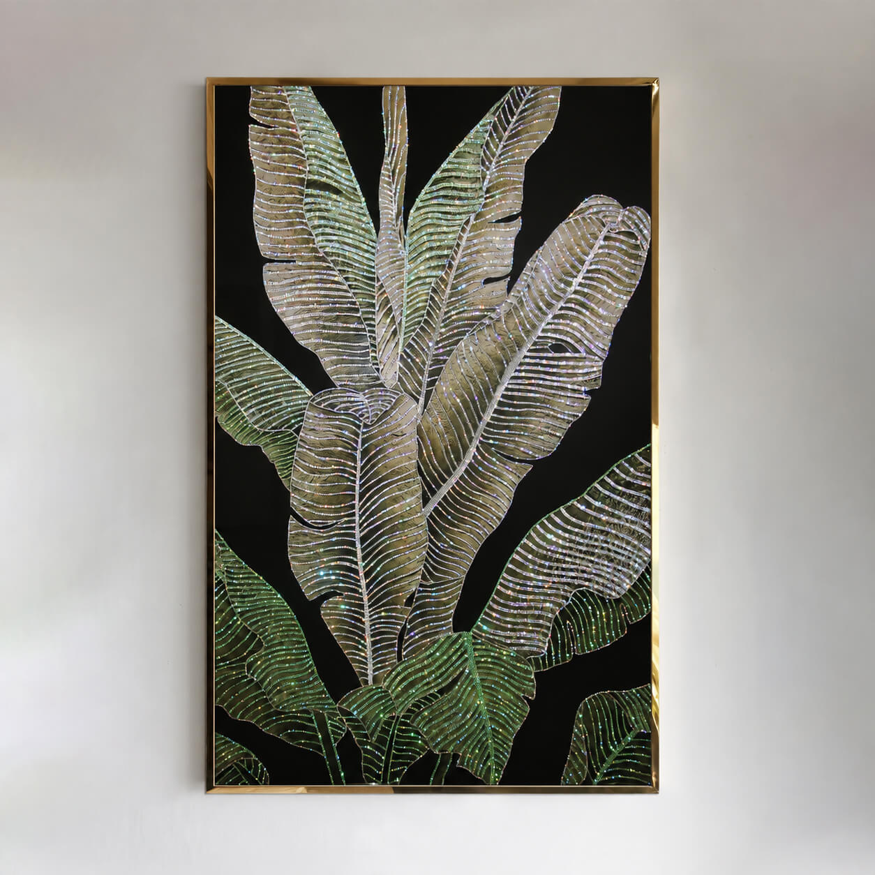 Front view of green and gold tropical leaves with crystal accents and a gold frame